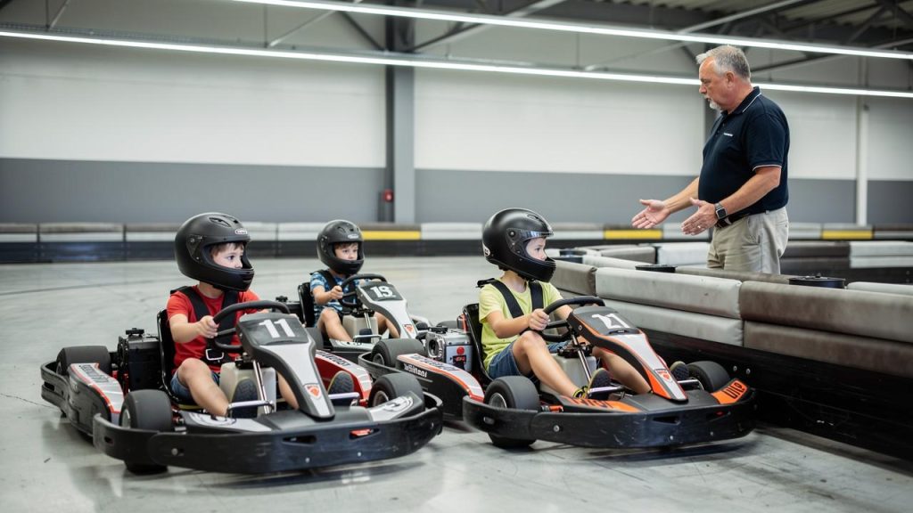 Tri deteta u karting kolima sa kacigama slušaju muškarca koji im daje instrukcije